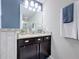 Bright bathroom featuring a blue accent wall, dark vanity, granite countertop, and modern light fixture at 4820 Battaglia Blvd, St Cloud, FL 34769