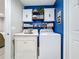 Bright laundry room with vibrant blue walls, white cabinetry, and modern washer and dryer setup at 4820 Battaglia Blvd, St Cloud, FL 34769