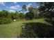 Image of a green grass lot with purple wildflowers and abundant trees under a partly cloudy blue sky at 510 Captiva Dr, Davenport, FL 33896