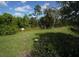 Image of a green grass lot with purple wildflowers and abundant trees under a partly cloudy blue sky at 510 Captiva Dr, Davenport, FL 33896