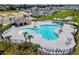 Aerial view of a community pool area with lounge chairs, palm trees, and a covered patio at 5591 Maddie Dr, Haines City, FL 33844