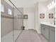 Bright bathroom featuring a glass enclosed shower, decorative accents, gray vanity with sink, and neutral toned tile flooring at 565 Big Pine Ave, Minneola, FL 34715