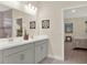 Bathroom featuring a double vanity with gray cabinets, neutral walls, and an adjacent bedroom with a partial view at 565 Big Pine Ave, Minneola, FL 34715