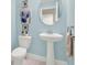 Powder room with a pedestal sink, light blue walls, and decorative accents at 565 Big Pine Ave, Minneola, FL 34715