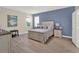 Comfortable main bedroom with plenty of light featuring a decorative blue accent wall and stylish furnishings at 565 Big Pine Ave, Minneola, FL 34715