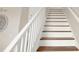 A brightly lit staircase features white painted rails, risers and stringers and stained hardwood treads at 565 Big Pine Ave, Minneola, FL 34715