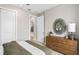 Bright bedroom with a rustic wood dresser, sunburst mirror, and view into the light hallway at 6257 Dew Drop Loop, St Cloud, FL 34771