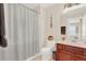 Neutral-toned bathroom with a gray striped shower curtain, dark wood cabinets, and a single-sink vanity at 6992 Brescia Way, Orlando, FL 32819