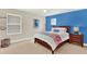 Bright bedroom with blue accent wall, large window, queen-size bed, and dark wood nightstand at 6992 Brescia Way, Orlando, FL 32819