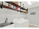 Functional laundry room featuring open shelving, modern washer and dryer, and a utility sink at 6992 Brescia Way, Orlando, FL 32819