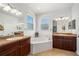 Bright bathroom with dual vanities, a soaking tub, and ample natural light from windows at 707 Brandy Oaks Loop, Winter Garden, FL 34787