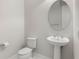 Bathroom features a pedestal sink, toilet, and circular mirror at 8742 European Fan Palm Aly, Winter Garden, FL 34787