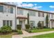 Inviting townhome showcasing lush green lawn, brick walkway, and colorful window shutters at 8742 European Fan Palm Aly, Winter Garden, FL 34787