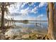 Scenic lake view featuring a dock, swing, trees, and rocks along the shore on a clear day with scattered clouds at 9243 Point Cypress Dr, Orlando, FL 32836