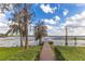 Wooden dock with a bench extending into the lake, surrounded by lush greenery and mature trees under a bright sky at 9243 Point Cypress Dr, Orlando, FL 32836