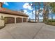 Home exterior featuring a three-car garage with a large driveway and lakeside trees at 9243 Point Cypress Dr, Orlando, FL 32836