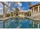 Covered swimming pool with swim-up bar, surrounded by neutral stone decking and enclosed with a screen at 9243 Point Cypress Dr, Orlando, FL 32836