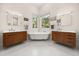 A luxury bathroom features double vanities, a soaking tub under large corner windows, and white tile floors at 9308 Thurloe Pl, Orlando, FL 32827