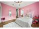 Pink bedroom features hardwood floors, a ceiling fan, a window and a closet with bi-fold doors at 9308 Thurloe Pl, Orlando, FL 32827