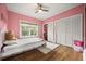 Pink bedroom features hardwood floors, a ceiling fan, a window and a closet with bi-fold doors at 9308 Thurloe Pl, Orlando, FL 32827