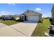 Well-manicured lawn and driveway lead to a modern home with a two car garage and blue shuttered windows at 944 Brooklet Dr, Davenport, FL 33837