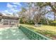 Spacious backyard with a patio, screened lanai, lush landscaping, and cozy seating area under mature trees at 10339 Manila Bay Dr, Orlando, FL 32821