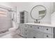 Bathroom features gray vanity with marble top, round mirror, and a tiled shower with mosaic flooring at 10339 Manila Bay Dr, Orlando, FL 32821