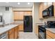 Bright kitchen featuring tile floors, wooden cabinetry, stainless steel sink and black appliances at 1270 Falling Star Ln, Orlando, FL 32828