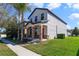 View of a two-story home showcasing its side and front with well-maintained green lawn and palm trees at 15088 Night Heron Dr, Winter Garden, FL 34787