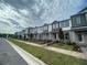 Street view of new townhomes with gray and white siding and well-manicured landscaping at 15364 Burgtheater Dr, Winter Garden, FL 34787