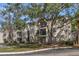 Exterior view of a multi-story apartment building with mature trees at 1948 Lake Atriums Cir # 129, Orlando, FL 32839