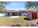 Spacious backyard with white fence, patio and chairs, lush lawn, and a red shed at 2491 Bracknell Forest Trl, Tavares, FL 32778