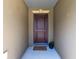 Covered entryway with a wood door, decorative trim, and a welcome mat at 2491 Bracknell Forest Trl, Tavares, FL 32778