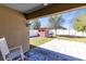 Covered patio with white rocking chair overlooking backyard with red shed and manicured lawn at 2491 Bracknell Forest Trl, Tavares, FL 32778