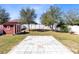 Backyard featuring a red shed and a patio against a backdrop of green lawn and trees at 2491 Bracknell Forest Trl, Tavares, FL 32778