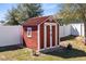 A charming red shed with a white trim in a backyard setting at 2491 Bracknell Forest Trl, Tavares, FL 32778