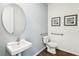 Modern powder room features a round mirror, framed artwork, and a sleek design at 2568 Kinsale Ln, Ormond Beach, FL 32174