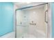 Bathroom shower featuring glass doors, built-in seat, grab bars, and bright turquoise wall paint at 4117 Fairview Vista Pt # 206, Orlando, FL 32804