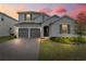 Charming two-story home with gray shutters, a brick driveway, and manicured landscaping at dusk at 4484 Lions Gate Ave, Clermont, FL 34711