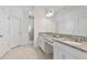 Well-lit main bathroom with dual granite sinks, undermount sinks, white cabinets, and a glass enclosed shower at 4484 Lions Gate Ave, Clermont, FL 34711