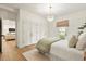 Bedroom with a crystal chandelier, white bedding, wooden floors, and double closets, connected to the living room at 535 N Interlachen Ave # 106, Winter Park, FL 32789
