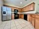 Well-lit kitchen featuring wood cabinets, stainless steel refrigerator, and black appliances at 6640 S Goldenrod Rd # 118B, Orlando, FL 32822
