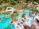 Aerial view of a resort with multiple pools, water features, slides, and lush landscaping at 7691 Heritage Crossing Way # C-1, Reunion, FL 34747