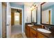 Bathroom with a double sink vanity, granite countertop, and view into the bedroom; spacious and functional at 7691 Heritage Crossing Way # C-1, Reunion, FL 34747