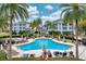Relaxing resort-style pool area with sun loungers, palm trees, and building views at 7691 Heritage Crossing Way # C-1, Reunion, FL 34747