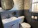 Charming half bathroom with modern fixtures, round mirror, and brick accent wall at 803 N Pine Hills Rd, Orlando, FL 32808