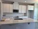 Bright kitchen with white cabinets, subway tile backsplash, stainless steel microwave, and an island with quartz countertop at 9338 Bolshoi Aly, Winter Garden, FL 34787