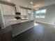 Well-lit kitchen with island featuring stone countertops, undermount sink, white cabinets and stainless steel appliances at 9338 Bolshoi Aly, Winter Garden, FL 34787
