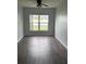 A bedroom featuring wood-look flooring, natural light from a window, and light gray walls at 1117 Cambourne Dr, Kissimmee, FL 34758