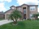 Two-story home with manicured lawn, complemented by palm trees and a driveway leading to an attached garage at 1117 Cambourne Dr, Kissimmee, FL 34758